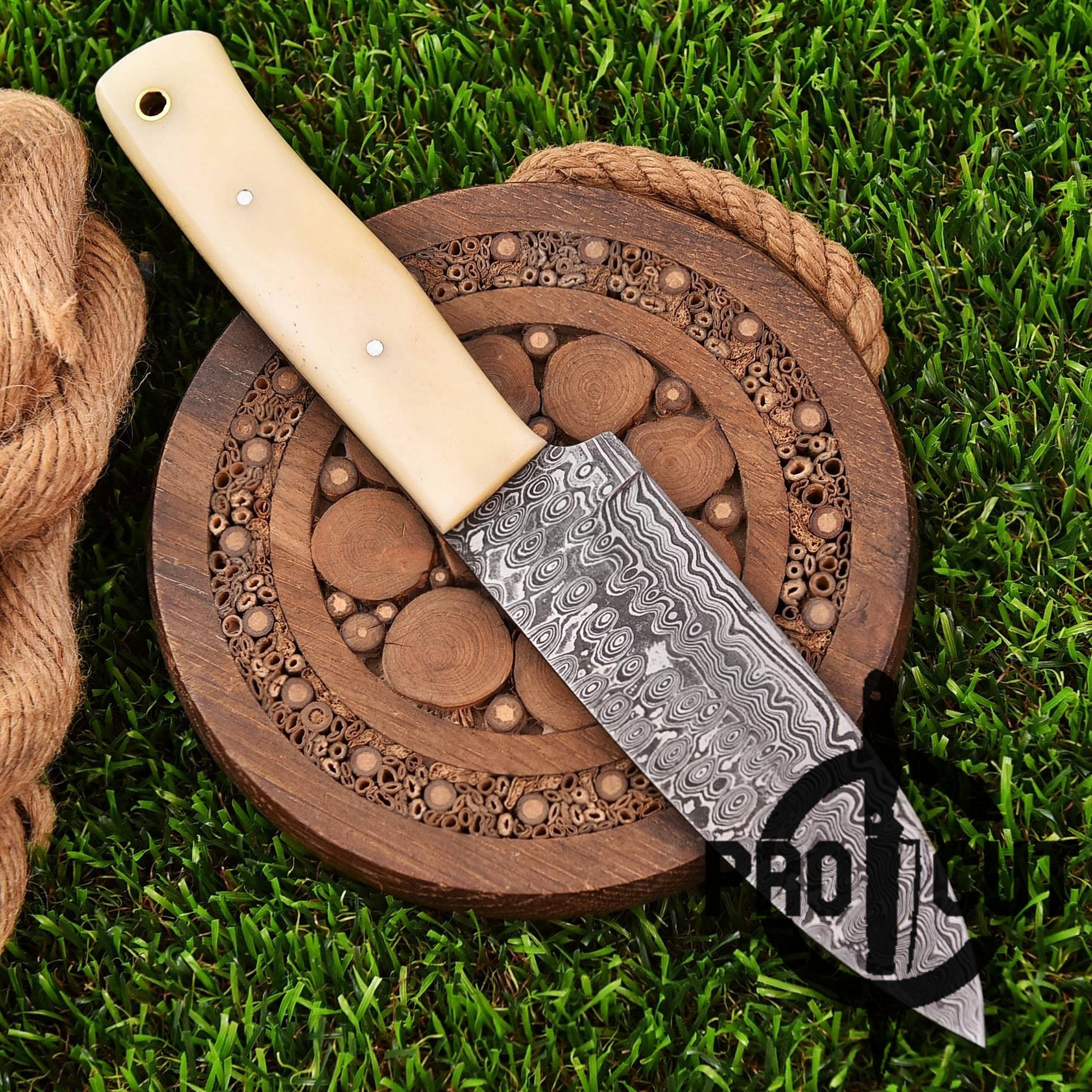 Decorative knife with a wooden handle on a wooden cutting board with a rope, on grass.